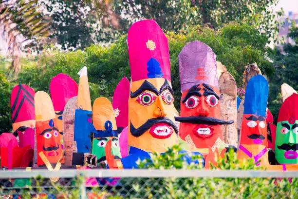 roadside streetside shot of huge paper mache effigies puppets of demon ravana being built in colorful paper to be burnt on the eve of dussehra Vijayadashami to be filled with fireworks for the hindu festival. Sold by poor artisans who make these in bulk to sell