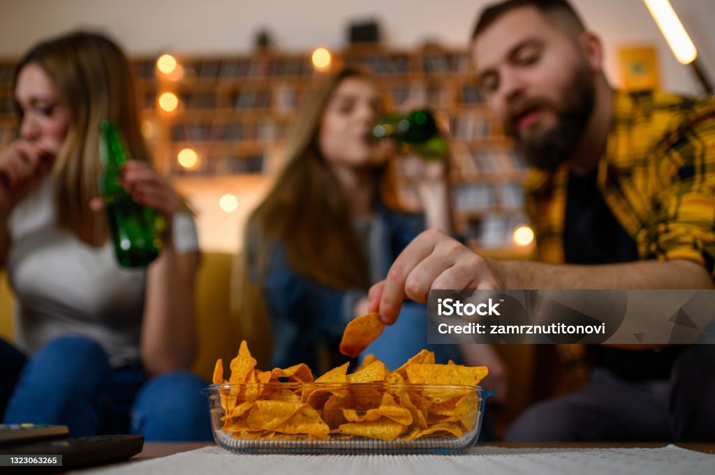Bowl of nachos on a house party Bowl of nachos on a house party while the blurry group of friends are having fun and drinking beer Sharing Stock Photo