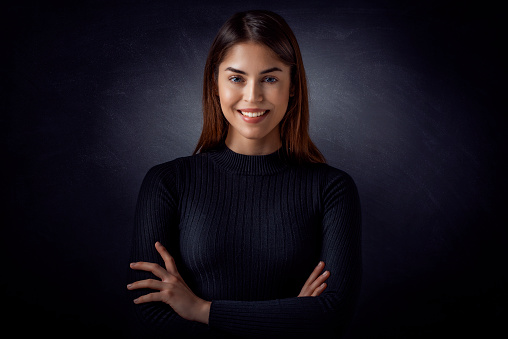 Studio portrait of beautiful brown hair woman standing at isolated at dark grey background.