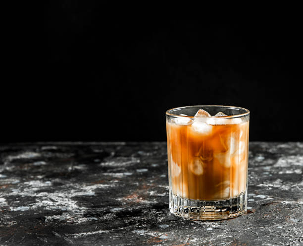 istock Cold coffee with ice and cream in a glass on a dark background. 1323065980