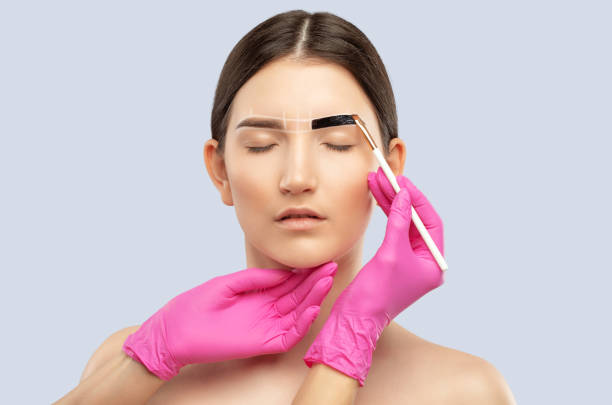 istock Make-up artist makes markings with white pencil for eyebrow and paints eyebrows. Professional makeup and facial care. 1323066049