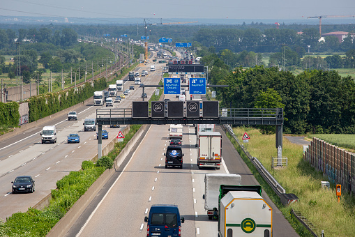 Weilbach, Germany - June 10, 2021: Large trucks and dense traffic on autobahn A3 near Wiesbadener Kreuz. The Bundesautobahn 3 (abbreviated as BAB 3 or A 3) is a highway in Germany that links the border to the Netherlands near Wesel in the northwest to the Austrian border near Passau in the southeast.