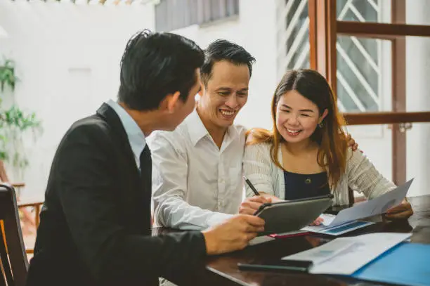 Photo of Happy Asian couple signing contract agreement from real estate agent