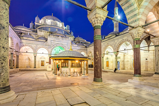 Man sits in the Inner Courtyard of the Beyazit Mosque (Beyazid II Mosque) in Istanbul,Turkey at twilight.