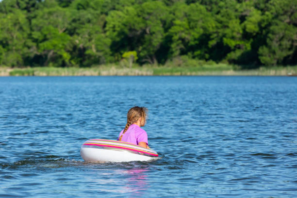 garota no anel de natação do tubo interno no lago no verão - inner tube swimming lake water - fotografias e filmes do acervo