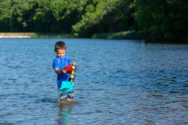istock Boy Playing With Toy Dump Truck in Lake 1323077802
