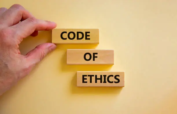 Code of ethics symbol. Wooden blocks with words 'Code of ethics'. Beautiful white background. Businessman hand. Copy space. Motivational, business and code of ethics concept.