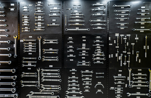 Close-up view of a well-organized toolbox containing various sizes of sockets, socket wrenches, and other related tools. The tools are metallic and show signs of use. They are neatly arranged in the black toolbox with specific slots for each tool.