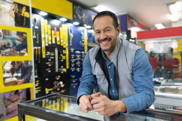 szczęśliwy sprzedawca pracujący za ladą w sklepie ze sprzętem - sklep z artykułami metalowymi zdjęcia i obrazy z banku zdjęć