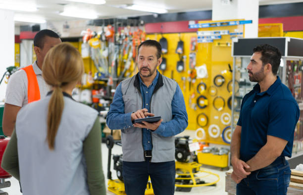 менеджер магазина разговаривает с группой сотрудников в хозяйственном магазине - construction equipment hand tool industry стоковые фото и изображения