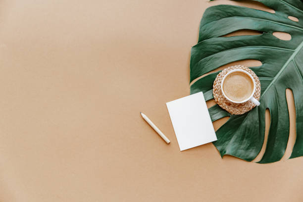 istock A simple trendy office Desk. Coffee cup, monstera leaf, blank card .Home Office desktop with space copying. Top view, copy space. Minimal concept 1323082984