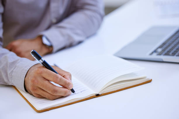 istock Cropped shot of an unrecognizable man making notes while sitting at his desk 1323085147