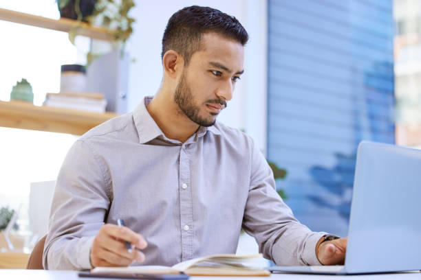 istock Shot of a businessman making notes while working on his laptop at his desk 1323085149