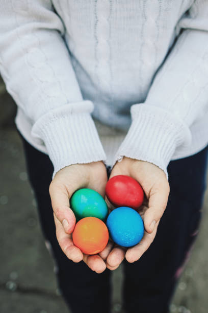 istock Female hands in a white fluffy sweater hold colorful easter eggs 1323085217