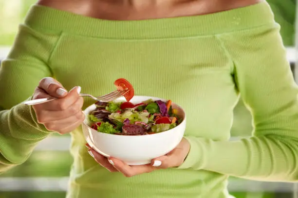 Close-up of a Hispanic cute young woman eating vegan salad at lunch