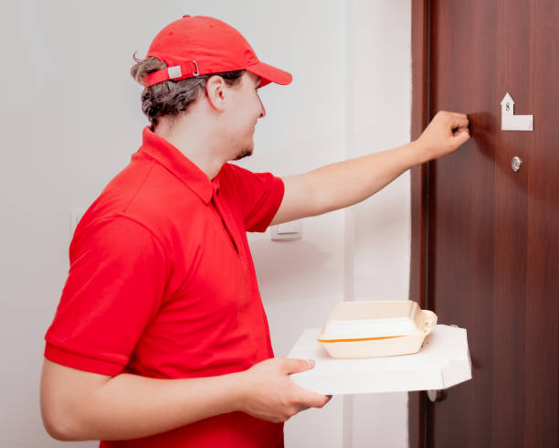 istock Delivery man smiling and knocking at the door 1323089160