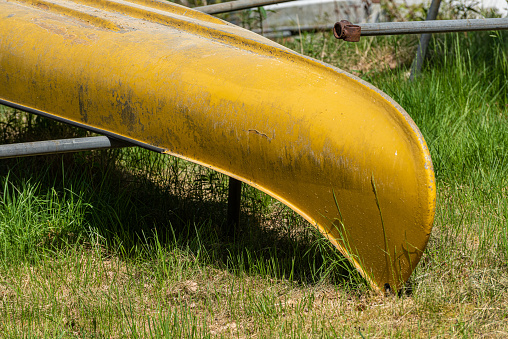 Yellow canoe upside down on land.