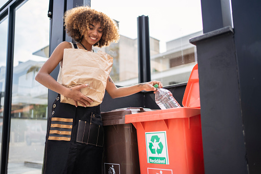 Mujer joven afroamericana reciclando basura. Concepto de sostenibilidad. photo