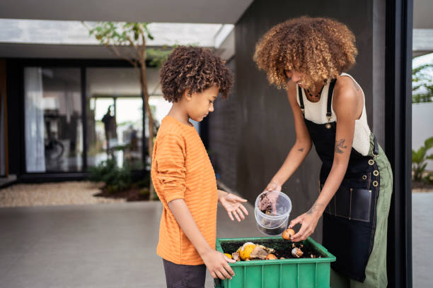 la giovane donna afroamericana e suo fratello minore fanno il compost dagli avanzi. concetto di sostenibilità. - spreco alimentare foto e immagini stock