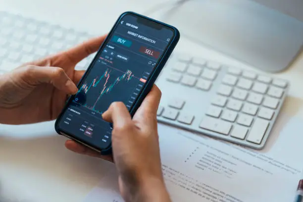 Photo of Close-up Shot of an Anonymous Woman Holding a Smartphone with a Stock Market Graph on Screen