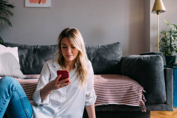 istock Beautiful Woman Using Mobile Phone at Home 1323098149