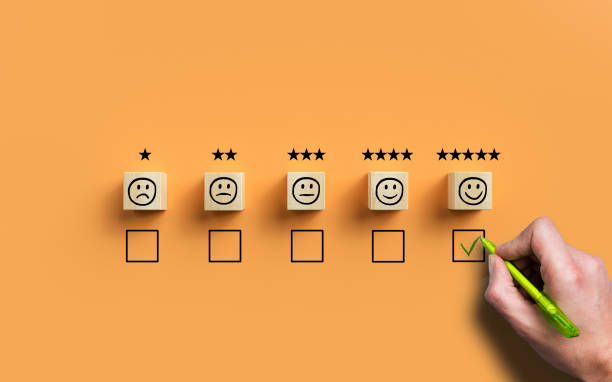 hand selecting a happy emoticon symbolizing a very good review hand selecting a happy emoticon symbolizing a very good review on orange background customer feedback stock pictures, royalty-free photos & images