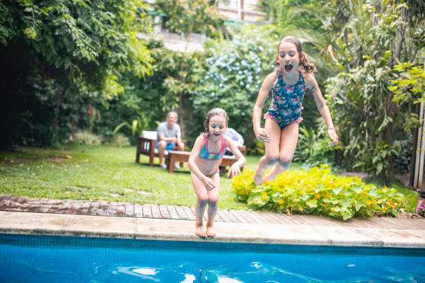 istock Carefree Young Sisters Jumping into Swimming Pool 1323107364