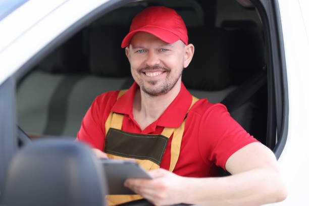 smiling portrait of male courier driver holding documents in car window - postal worker truck driver delivering delivery person imagens e fotografias de stock