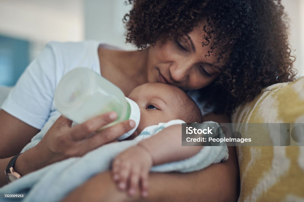 Shot of an adorable baby girl being bottle fed by her mother on the sofa at home Milk is always on the menu Baby - Human Age Stock Photo