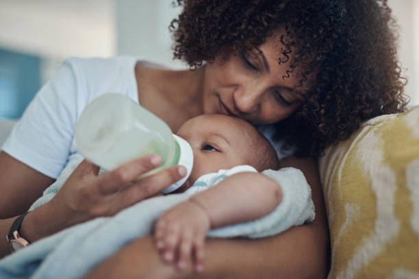 Shot of an adorable baby girl being bottle fed by her mother on the sofa at home Milk is always on the menu mother stock pictures, royalty-free photos & images