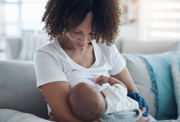 Shot of a young woman breastfeeding her adorable baby girl on the sofa at home As natural as nature intended breastfeeding photos stock pictures, royalty-free photos & images