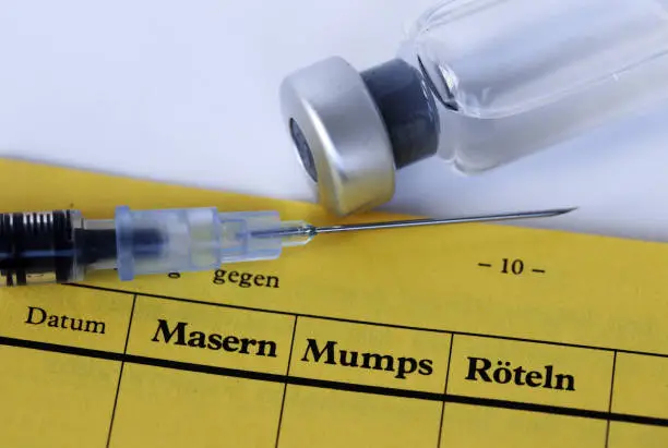 Vaccination against measles, mumps and rubella with vaccination card, syringe and vaccine