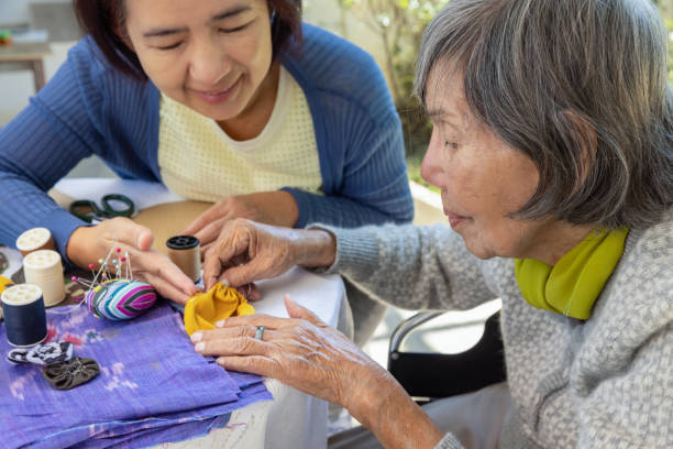 elderly woman and daughter in the needle crafts occupational therapy for alzheimer’s or dementia - japanese ethnicity women asian and indian ethnicities smiling imagens e fotografias de stock