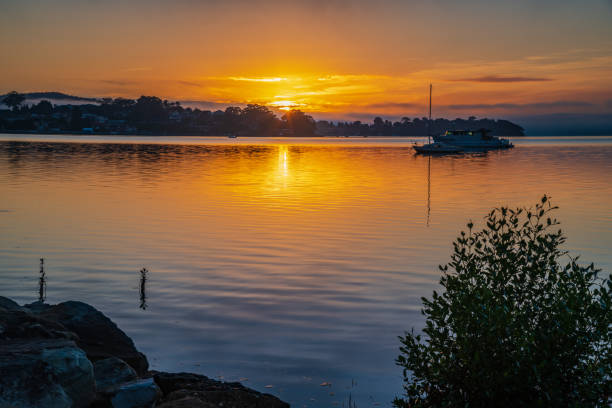 istock Sunrise waterscape with boats, light cloud and fog 1323127444