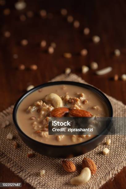 Close Up Of A Famous Bengali Dessert Nolen Gurer Chanar Payesh Or Milk Pudding Of Cottage Cheese In A Black Bowl Topdown View Wooden Background Stock Photo - Download Image Now