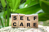 Self care word on wood cubes on green nature background.
