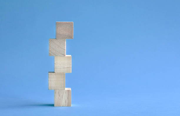 istock 5 letter blank and wood block stacked up. On blue background. 1323129898
