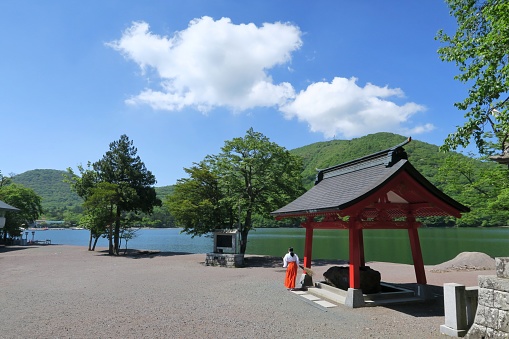 View of Lake Onuma and a Miko (shrine meiden) from Akagi shrine main building in Akagi, Gunma, Japan. June 9, 2021.