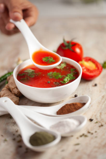 신선한 고수 잎과 재료와 허브로 장식된 인도 홈메이드 신선하고 건강한 토마토 수프를 조미료 가미가 곁들인 화이트 세라믹 그릇에 담겨 제공됩니다. - tomato soup red basil table 뉴스 사진 이미지
