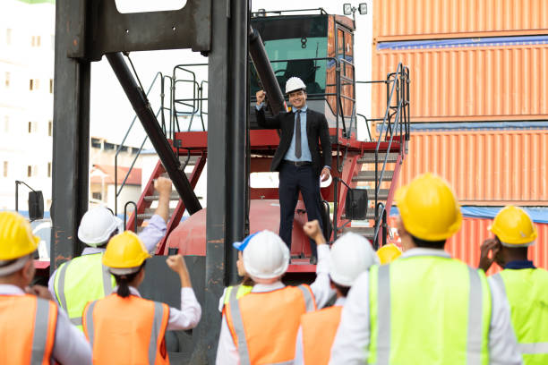 istock warehouse boss engineer standing on crane car with factory workers raise hand for congratulations in containers warehouse storage 1323138290