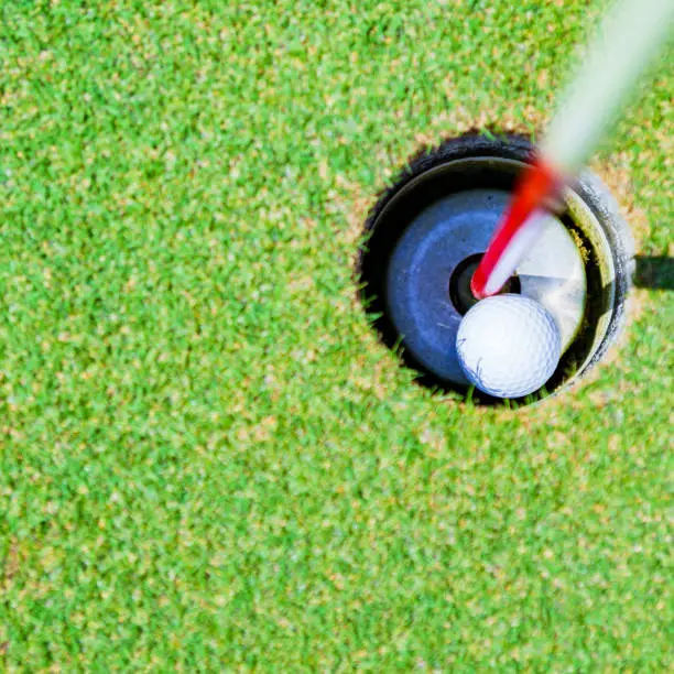 Photo of golf ball in the cup of green