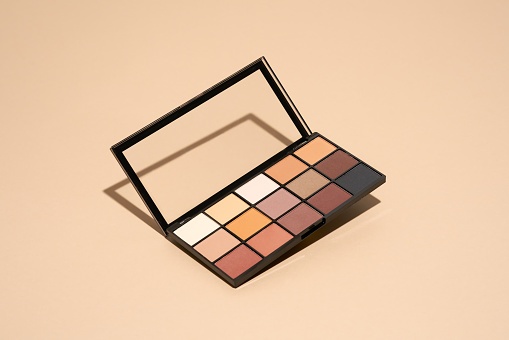 Make-up palette floating over a beige background. Professional multicolor eye shadow make-up palette. Cosmetic products