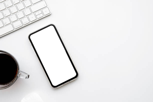 istock White office desk table with smartphone with blank mockup screen, cup of coffee and computer keyboard. Top view with copy space, flat lay. 1323146565
