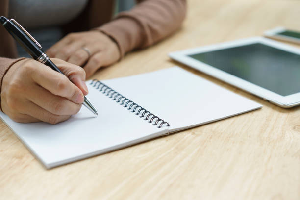 istock Woman hand with pen writing on notebook. 1323146746