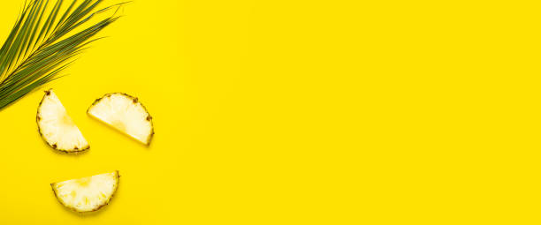 istock Ripe pineapple slices and a palm leaf on a yellow background. Top view, flat lay. Banner 1323153210