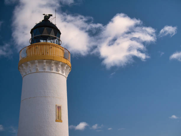 Designed by brothers David and Thomas Stevenson, Bressay Lighthouse on a sunny day, agains a blue sky with white clouds.