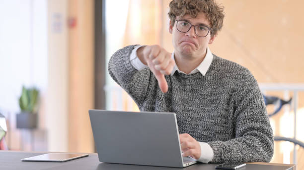 istock Young   Man with Laptop showing Thumbs Down 1323158389