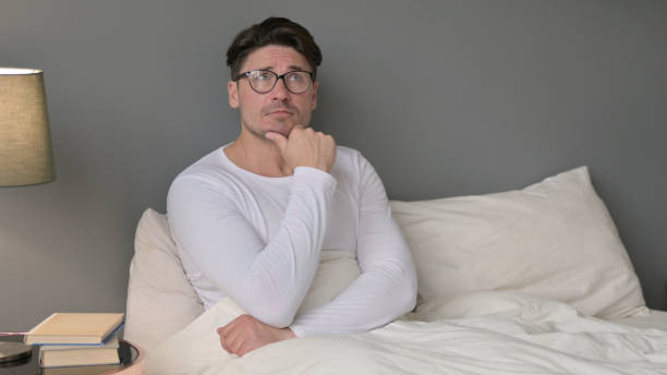 istock Pensive Middle Aged Man Brainstorming in Bed 1323158510