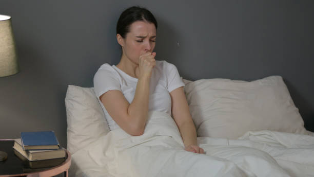 istock Young Woman with Cough Sitting in Bed 1323158519