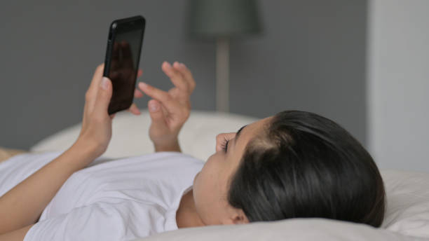 istock Indian Woman using Smartphone Laying in Bed 1323158817